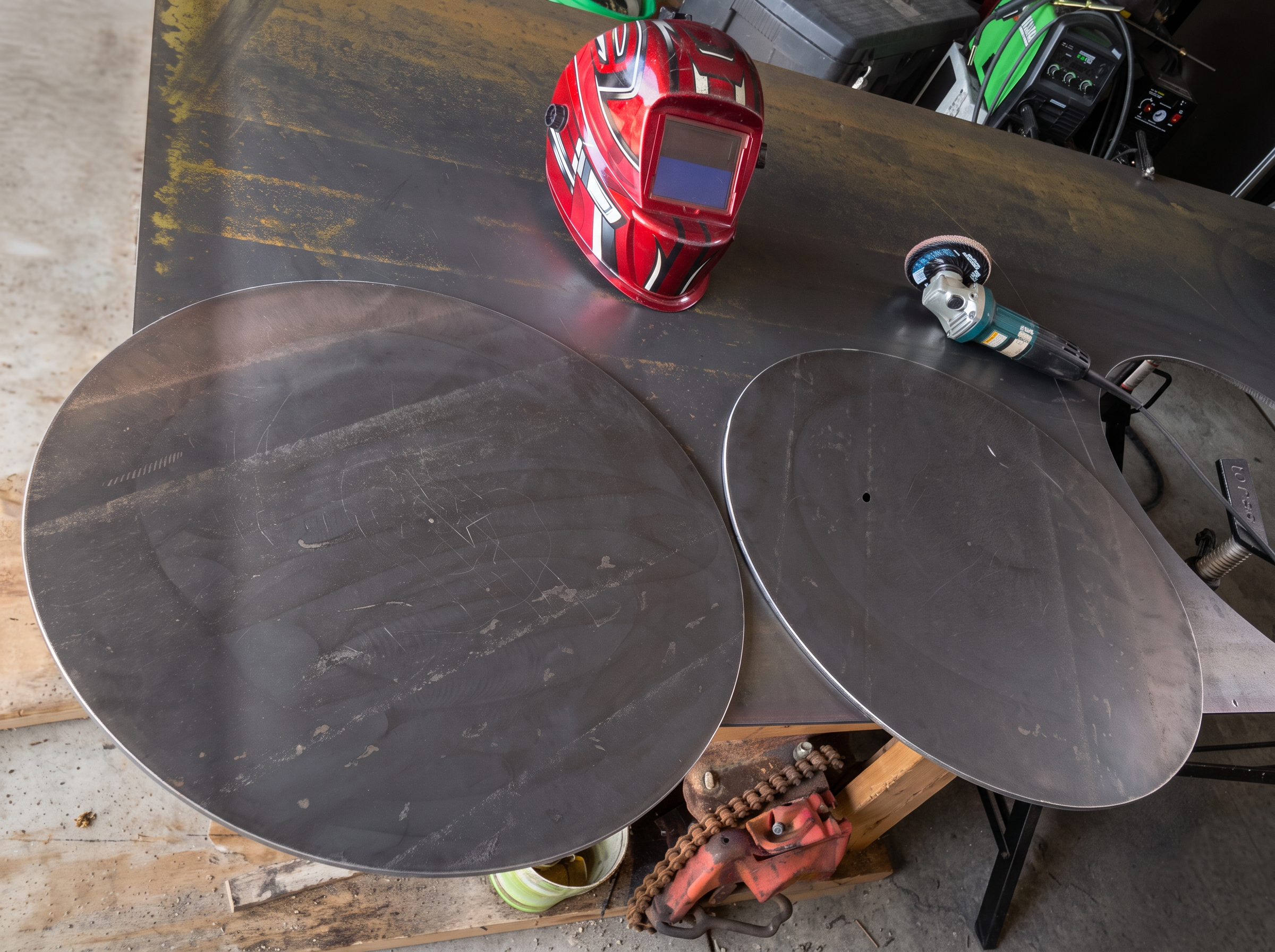 Two round steel cooking plates on a workbench